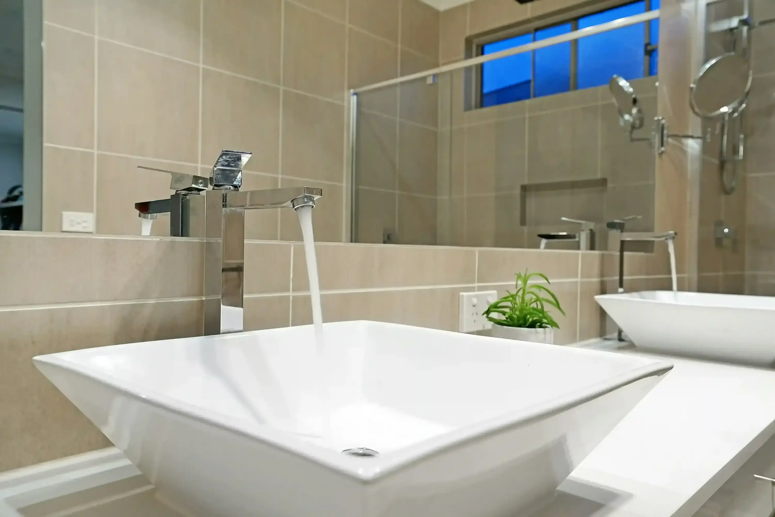 A running faucet in a modern bathroom setting.