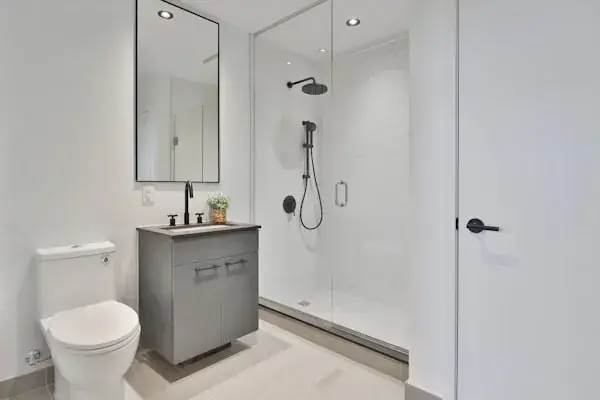 Modern bathroom with white marble walls, a rectangular white bathtub, black fixtures including a wall-mounted showerhead and faucet, and a window providing natural light.